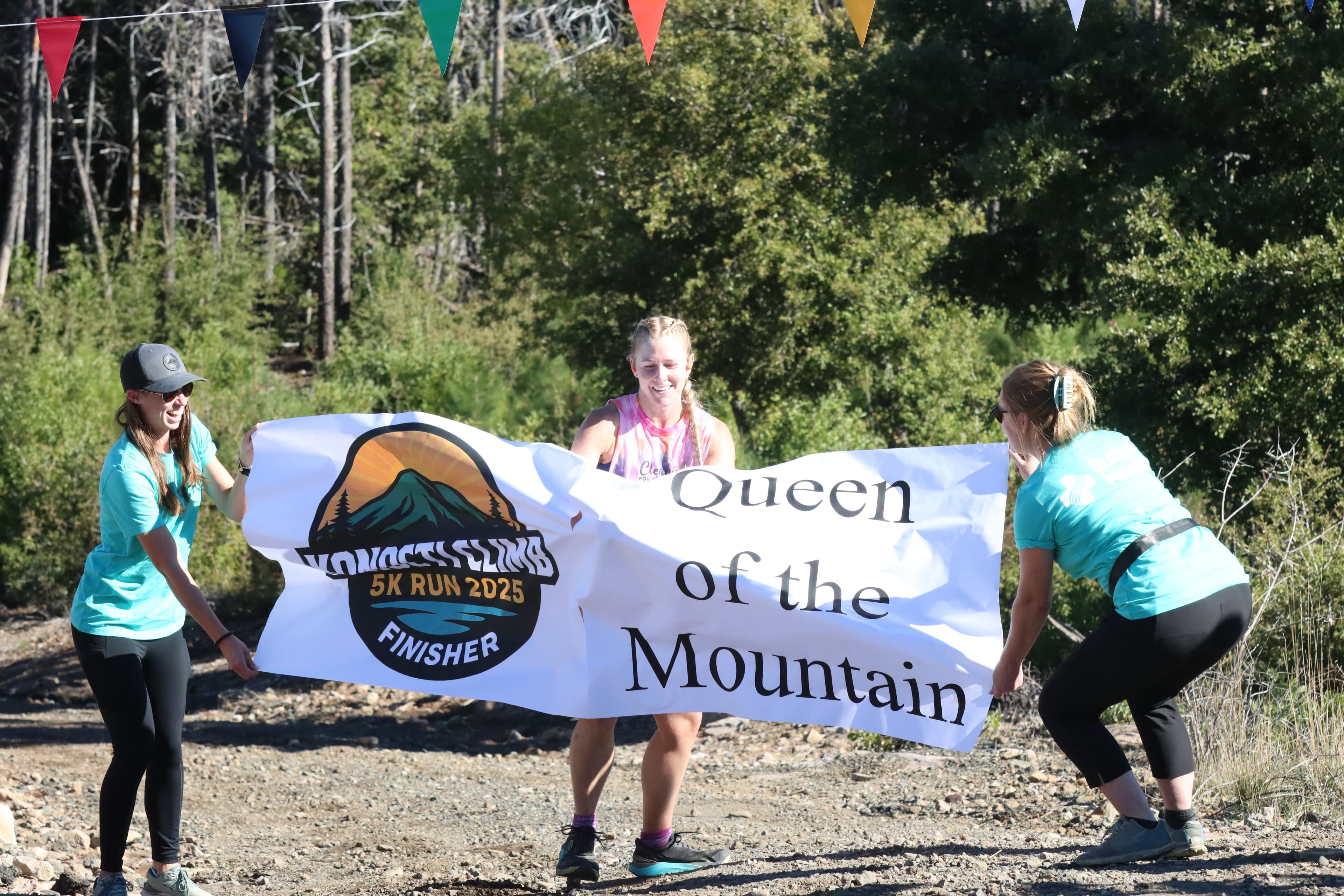 The 2025 Queen of the Mountain breaking the finish banner at Konocti Climb.